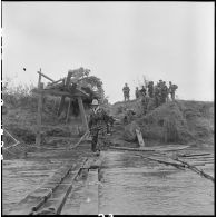 Des légionnaires du 1er bataillon étranger de parachutistes (BEP) franchissent la Nam Youm sur un pont de fortune.
