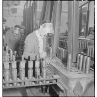Plan général d'un atelier de l'usine de munitions où des ouvriers travaillent à la confection d'obus.