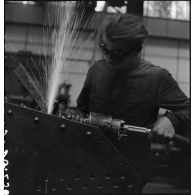 A l'atelier d'Issy-les-Moulineaux un ouvrier meule une plaque de blindage de char B1 bis.