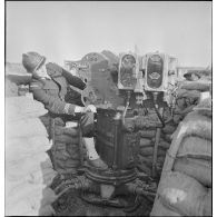 Un lieutenant de vaisseau, appartenant à la 4e batterie mobile de défense antiaérienne de la Marine, s'installe sur un télépointeur (poste optique) qui détermine le pointage des canons de 90 mm CA (contre avions) modèle 1939.