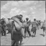Des prisonniers capturés au cours de l'opération Tourbillon 2 sont dirigés vers des camions dans lesquels ils vont être transportés.