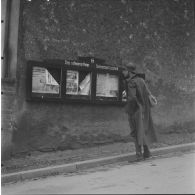 [Un fantassin de la 42e DI (division d'infanterie) se trouve dans une rue de Lauterbach (Sarre) devant un panneau du journal de la Waffen-SS 