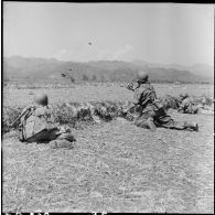 A Diên Biên Phu, un parachutiste lance une grenade vers une position occupée par le Viêt-minh à l'arrière-plan.