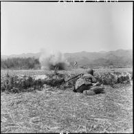 A Diên Biên Phu, des parachutistes se mettent à couvert pendant qu'explose devant eux une grenade, avant de s'élancer à l'assaut de la position occupér par le Viêt-minh à l'arrière-plan.