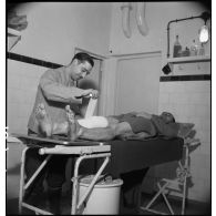 A l'infirmerie de l'ouvrage de Velosnes un infirmier soigne un soldat du 155e RIF blessé à la jambe.