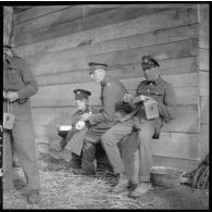 Des soldats anglais de la BEF mangent assis près d'un baraquement.