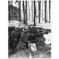 Deux soldats de la 4e armée sont photographiés de dos dans un trou de combat avec des grenades défensives.