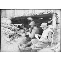 Deux soldats de la 4e armée qui servent un FM 24/29 dans un poste de combat lisent du courrier.