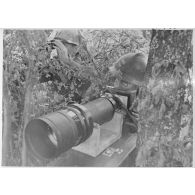 Un photographe utilise un appareil photo avec un téléobjectif dans le secteur de la 4e armée.