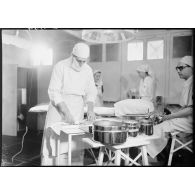 Dans la salle d'opérations d'un hôpital militaire un chirurgien est secondé par des infirmières britanniques de la Formation Hadfield Spears.