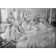 Dans la salle commune d'un hôpital militaire une infirmière britannique discute avec des blessés et des malades.