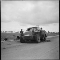 Un soldat français observe un véhicule allemand abandonné au bord d'une route.