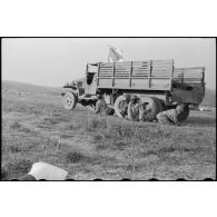 Un camion sanitaire GMC sur lequel flotte un drapeau blanc sert d'abri à des soldats alors que l'artillerie Viêt-minh pilonne la piste du camp retranché de Diên Biên Phu.