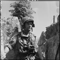 Le photographe du Service presse information (SPI) Jean Péraud, avec son appareil photographique Leica, dans une tranchée d'Isabelle à Diên Bien Phu.