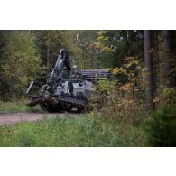 Un véhicule blindé Trojan des Royal Engineers britanniques progresse sur un chemin forestier à Tapa, en Estonie.
