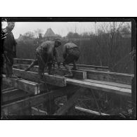 Soissons (Aisne). Construction d'un pont sur l'Aisne. Le perçage des traverses. [légende d'origine]