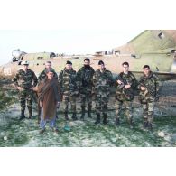 Photographie de groupe avec un Afghan devant une épave d'avion de combat MIG soviétique à l'aéroport de Mazar e Charif lors de la visite du général de division aérienne Gaviard, sous-chef d'état-major Opérations de l'EMA (état-major des armées) et du colonel Saillard, RepFrance (représentant des éléments français).