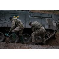 Des soldats britanniques déblaient la boue autour de la chenille d'un char Warrior embourbé en forêt de Tapa, en Estonie.