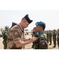 Un officier du GTD Bir Hakeim (groupement tactique désert) décore un soldat du détachement cambodgien de la médaille de la MINUSMA (mission multidimensionnelle intégrée des Nations Unies pour la stabilisation au Mali) lors d'une cérémonie sur la PFDR (plateforme désert relai) de Kidal.