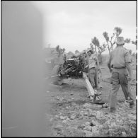 Deux servants autour d'un obusier M2A1, de type américain, de calibre 105 mm, vu de l'arrière.