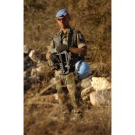 Portrait d'un militaire du RMT (régiment de marche du Tchad) en faction, effectuant la protection d'une zone lors d'une patrouille. Coiffé du béret bleu de l'ONU (Organisation des Nations unies), il porte son casque bleu à la ceinture.