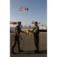 Un capitaine commandant d'unité reçoit son fanion des mains du lieutenant-colonel B. de Robien, chef de corps du 601e RCR et nouveau commandant du 420e DIM. En arrière-plan le mât des couleurs et un transport de troupes M-113 aux couleurs de l'ONU (Organisation des Nations unies).