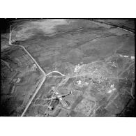 Avion Morane-Saulnier survolant un cantonnement situé près d'une route lors d'un vol de reconnaissance au-dessus du delta du Tonkin.
