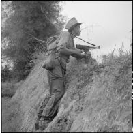 Un soldat se poste derrière une butte de terre, arme au poing.