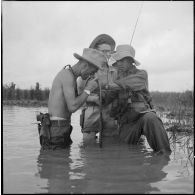 Dans l'eau jusqu'à la taille, des soldats allument une cigarette.