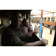 Congolais dans le couloir d'une voiture de train en gare.
