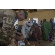 Un médecin du 2e régiment étranger de parachutistes (REP) effectue un test de détection de la malaria auprès d'un jeune garçon à l'école de santé de Ménaka, au Mali.