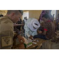 Un médecin du 2e régiment étranger de parachutistes (REP) effectue un test de détection de la malaria auprès d'un jeune garçon à l'école de santé de Ménaka, au Mali.