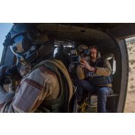 Un opérateur vidéo de la chaîne Canal+ filme un membre opérationnel de soute (MOS) à bord d'un hélicoptère Puma SA-330 en vol au-dessus du Sahel.
