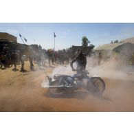 Un civil malien fait fumer sa moto au passage des troupes françaises à Korioumé, au Mali.