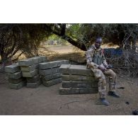 Un soldat malien empile des caisses de munitions trouvées dans un campement de terroriste dans la région d'Imenas, au Mali.