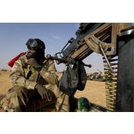 Un militaire malien sécurise le périmètre au moyen d'une mitrailleuse lourde DShK à l'arrière d'un pick-up lors de la traversée de Bourem, au Mali.