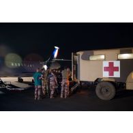 Le personnel médical débarque un blessé depuis une ambulance pour son évacuation à bord d'un avion Falcon 2000 sur l'aérodrome de Gao, au Mali.