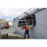 Des matelots de la frégate Ventôse manoeuvre la passerelle pour relier le bâtiment au quai de la base navale de Fort-de-France, en Martinique.
