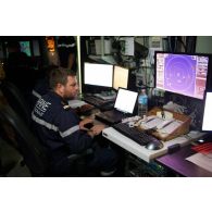 Un enseigne de vaisseau consulte la carte maritime au centre opérationnel de la frégate Ventôse en mer des Caraïbes.