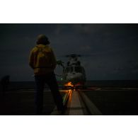 Un chien jaune guide le décollage d'un hélicoptère Panther AS-565 de la flottille 36F depuis la frégate de surveillance Ventôse pour une mission nocturne en mer des Caraïbes.