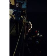 Un nacrotrafiquant monte à bord de la frégate de surveillance Ventôse par l'échelle de coupée sous la surveillance d'un marin, en mer des Caraïbes.