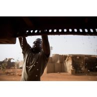 Un waterboy sangle un bac souple d'eau à son camion pour le remplissage des citernes à Gao, au Mali.