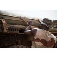 Le caporal-chef Mohamed sangle un bac souple d'eau à la plateforme de son camion TRM-10000 pour le remplissage des citernes à Gao, au Mali.