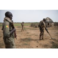 Un soldat malien sécurise le périmètre d'une vérification de non pollution (VNP) menée par des sapeurs du 2e régiment étranger de génie (REG) autour d'une habitation du secteur de N'Daki, au Mali.