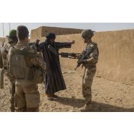 Des soldats contrôlent un habitant venu pour une consultation médicale à In Arabane, au Mali.