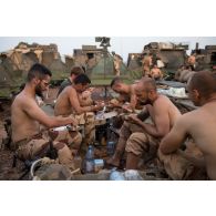 Des chasseurs du 7e bataillon de chasseurs alpins (BCA) mangent leur portion boeuf-carottes tirée de leur ration de combat lors d'un bivouac dans le Gourma malien.