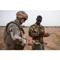 Des pyrotechniciens français et maliens retirent les relais de poudre de la queue d'un obus de 120 mm pour sa destruction sur un polygone d'explosion à Gao, au Mali.