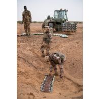 Un pyrotechnicien du détachement des munitions (DETMu) dépose des charges projectiles d'obus de 120 mm dans un fourneau sur un polygone d'explosion à Gao, au Mali.