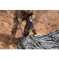 Un pyrotechnicien du détachement des munitions (DETMu) verse des billes explosifs sur des obus pour leur destruction sur un polygone de tir à Gao, au Mali.
