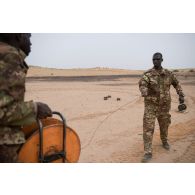 Des pyrotechniciens maliens déroulent du cordon détonnant pour la destruction de munitions sur un polygone d'explosion à Gao, au Mali.